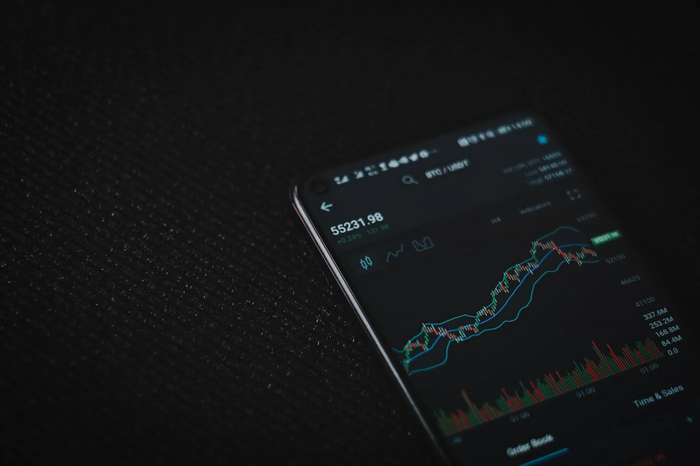 A phone showing a dark trading screen, a stock photo used for illustration rather than the Arcus app