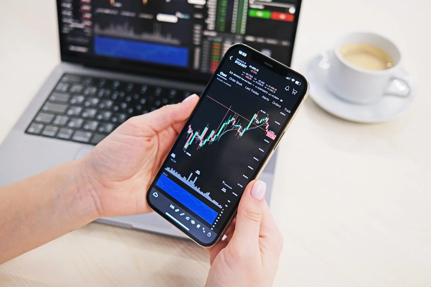 A phone and a laptop side by side showing market charts